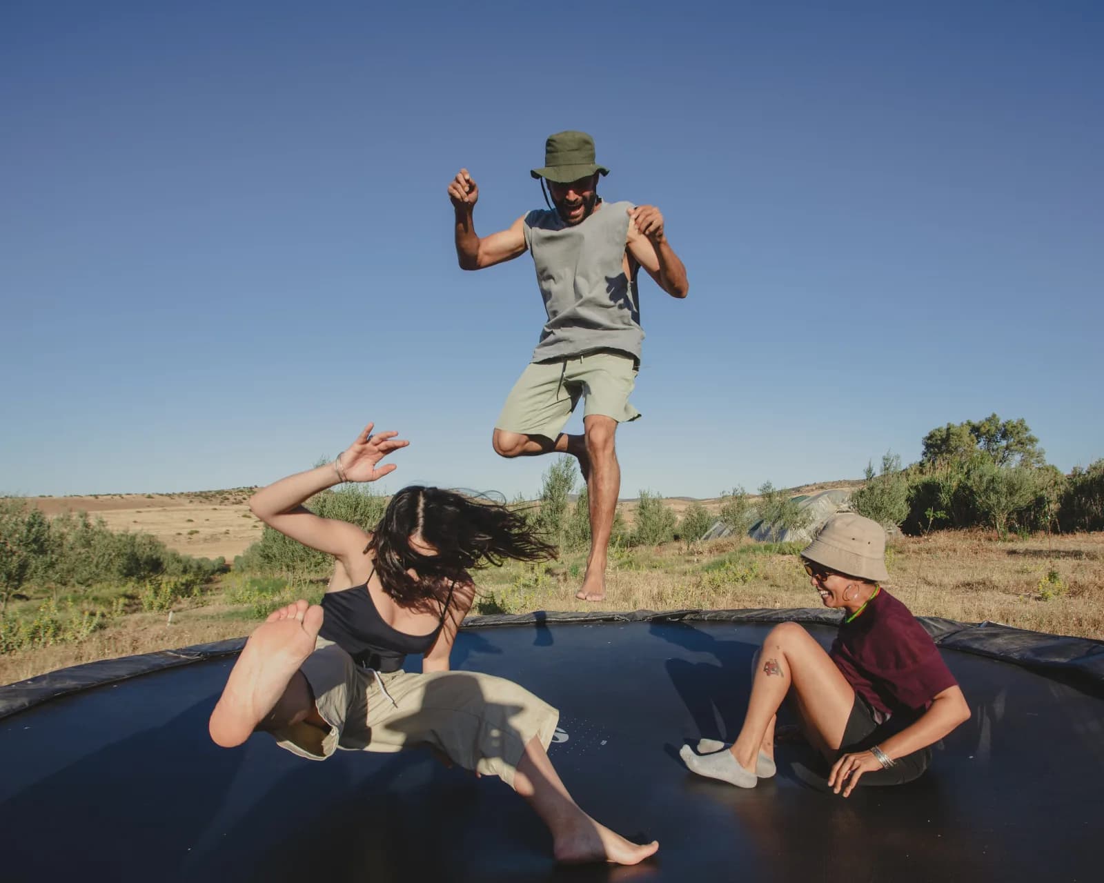 Mahdi jumping on the trampoline with two children at Farm El Baya