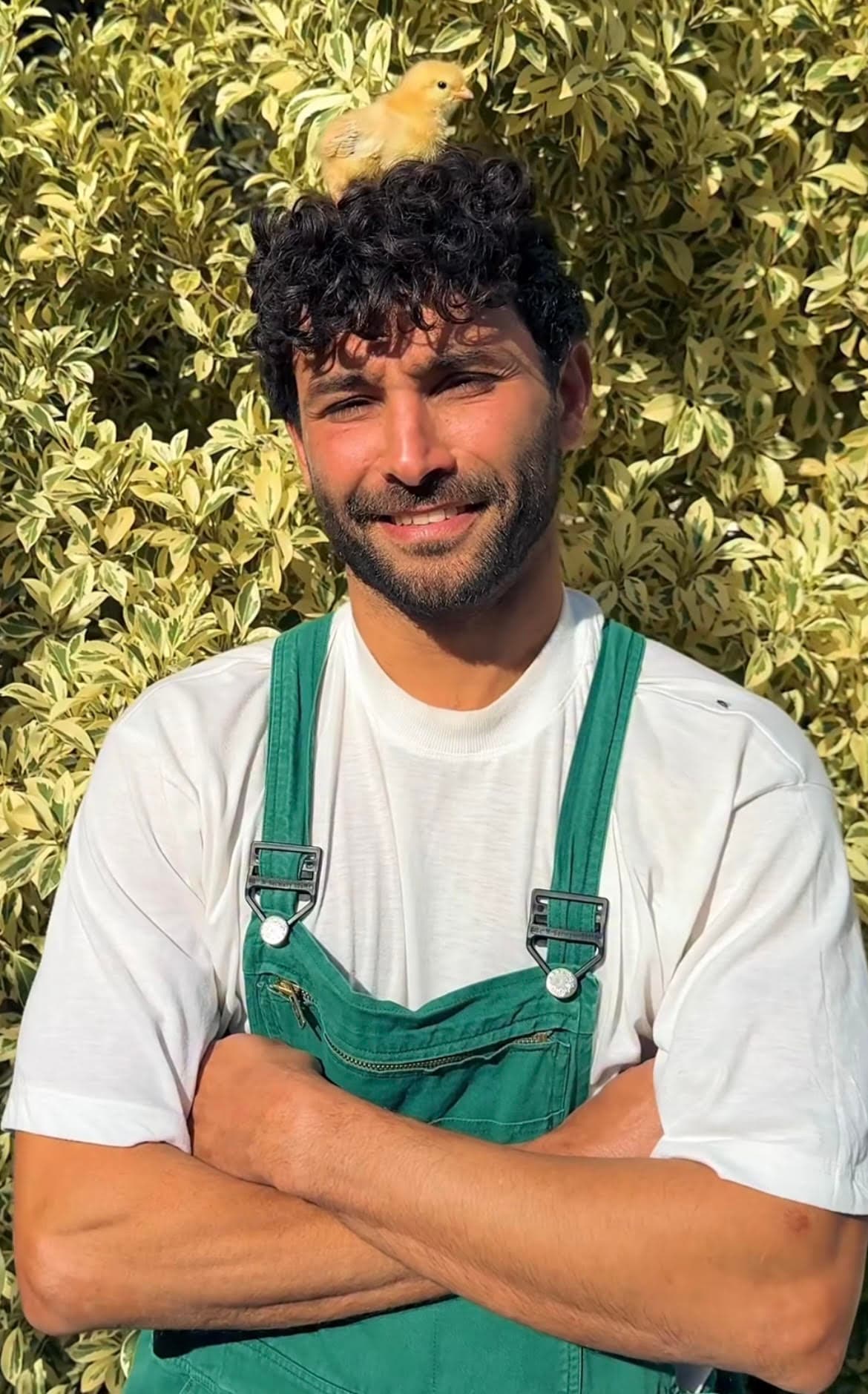 Mahdi smiling with a young chick perched on his head at Farm El Baya