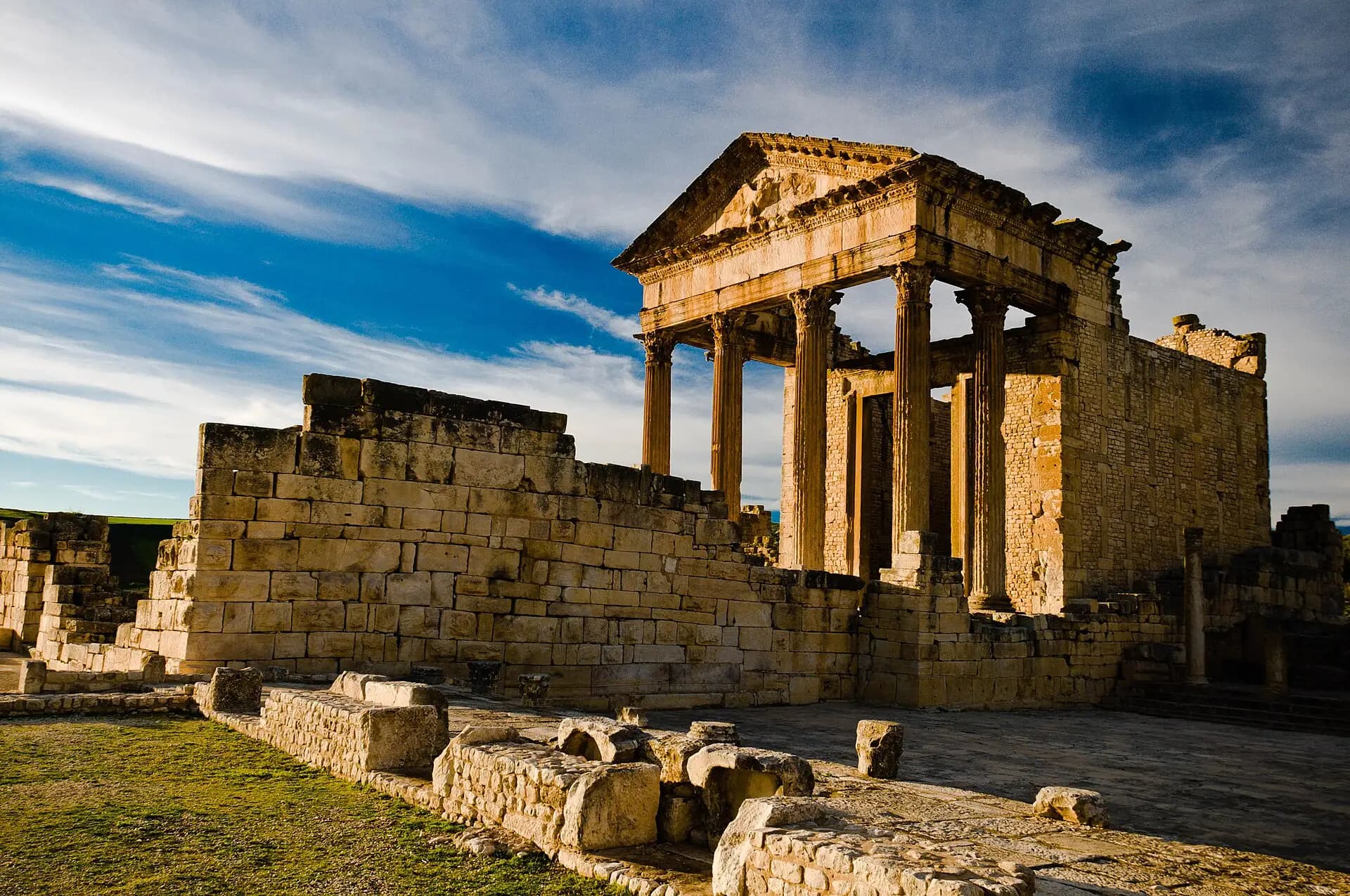 The Roman capitol of Dougga in golden light, its columned portico against the sky