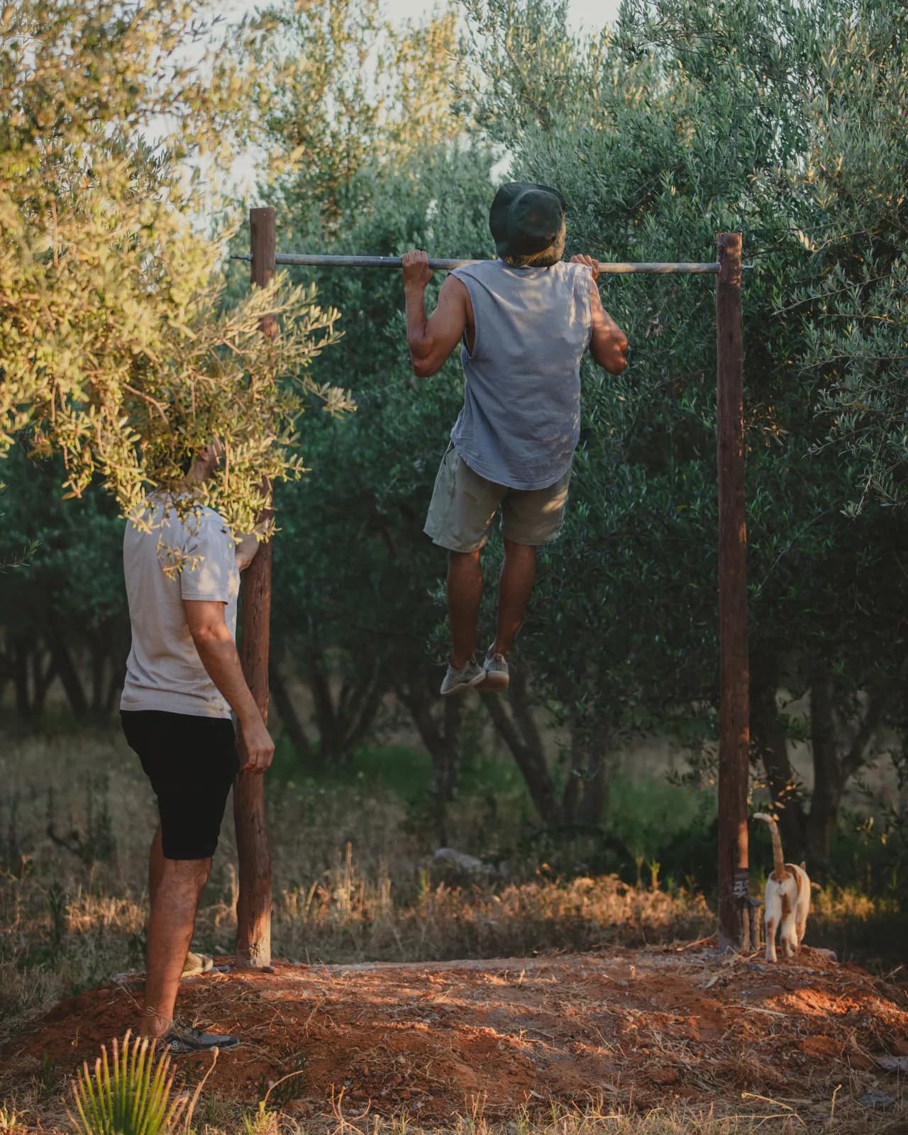 Mahdi doing pull-ups on a bar between trees at Farm El Baya